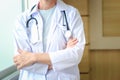 Confident female doctor in white workwear with stethoscope, standing with arms crossed in clinic hospital. Professional senior Royalty Free Stock Photo