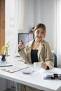 Female employee hand holding coffee cup and smiling to camera while sitting at her office desk. Royalty Free Stock Photo