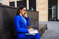 Confident female employer talking via mobile pone and writing notary in textbook Royalty Free Stock Photo