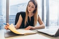 Confident female entrepreneur planning her workday sitting at her desk holding pen thinking looking at notebook in Royalty Free Stock Photo