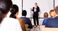 Confident female lecturer speaking to businesspeople at seminar