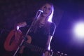 Confident female singer performing with guitar in nightclub Royalty Free Stock Photo