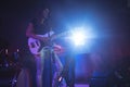 Confident female singer playing guitar on illuminated stage in nightclub Royalty Free Stock Photo