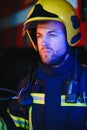 Confident fireman wearing protective uniform standing next to a fire engine in a garage of a fire department Royalty Free Stock Photo