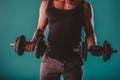 Confident, fit man flexing muscles with six-pack torso on turquoise background. Fitness instructor and model.