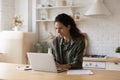 Confident focused woman using laptop, working online in kitchen Royalty Free Stock Photo