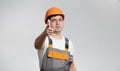 Confident foreman pokes finger into camera, construction worker points to you on grey studio background