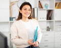 Girl with a folder of documents stands next to the workplace in the office Royalty Free Stock Photo