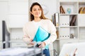 Girl with a folder of documents stands next to the workplace in the office Royalty Free Stock Photo