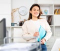 Girl with a folder of documents stands next to the workplace in the office Royalty Free Stock Photo