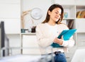 Manager girl is standing in the office and filling out documents on a folder Royalty Free Stock Photo