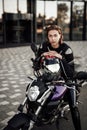 Confident girl in a motorcycle jacket sits with a motorcycle helmet on a motorbike Royalty Free Stock Photo