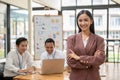 A confident Asian businesswoman stands with her arms crossed in a meeting room Royalty Free Stock Photo