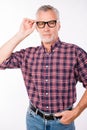 Confident gray aged man with glasses keeping his hands in pockets