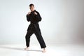 Confident guy in black kimono fighter posing in karate stance on studio background with copy space, mix fight concept Royalty Free Stock Photo