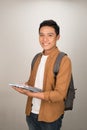 Confident handsome Asian student holding books and smiling at camera Royalty Free Stock Photo