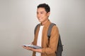 Confident handsome Asian student holding books and smiling at camera Royalty Free Stock Photo