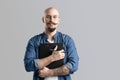 Confident handsome balded beard with musctache man wearing casual clothes holding clipboard isolated over gray