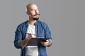 Confident handsome balded beard with musctache man wearing casual clothes holding clipboard isolated over gray