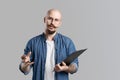 Confident handsome balded beard with musctache man wearing casual clothes holding clipboard isolated over gray