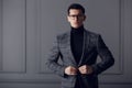 Confident,handsome man of affairs in black eyeglasses, black turtleneck and gray plaid jacket looks serious at camera. Royalty Free Stock Photo