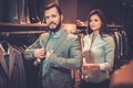 Confident handsome man with beard choosing a jacket in a suit shop. Royalty Free Stock Photo