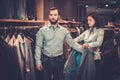 Confident handsome man with beard choosing a jacket in a suit shop. Royalty Free Stock Photo