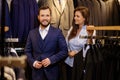 Confident handsome man with beard choosing a jacket in a suit shop. Royalty Free Stock Photo