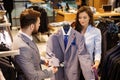 Confident handsome man with beard choosing a jacket in a suit shop. Royalty Free Stock Photo