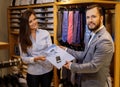 Confident handsome man with beard choosing a shirt in a suit shop. Royalty Free Stock Photo