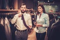 Confident handsome man with beard choosing a tie in a suit shop. Royalty Free Stock Photo