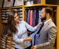 Confident handsome man with beard choosing a tie in a suit shop. Royalty Free Stock Photo