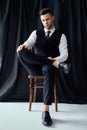 Confident handsome man in elegant suit posing sitting in chair