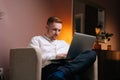 Confident handsome man using laptop while sitting in soft armchair Royalty Free Stock Photo