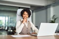 Confident happy young African American woman sitting at office desk, portrait. Royalty Free Stock Photo