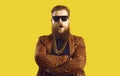 Eccentric bearded man in leopard print jacket with gold neck chain standing arms crossed Royalty Free Stock Photo