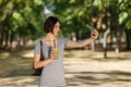 Beautiful girl taking a selfie. Woman with a smoothie on a blurred park background. Taking pictures concept. Copy space. Royalty Free Stock Photo