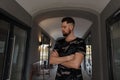 Confident and hipster handsome young man with a stylish hairstyle and brutal beard in a military camouflage fashionable T-shirt Royalty Free Stock Photo