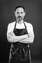 Confident in his culinary craft. Cook with beard and mustache wearing apron red background. Man mature cook posing