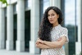 Confident hispanic businesswoman with curly hair on office building background Royalty Free Stock Photo