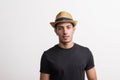 A confident hispanic young man with hat and black T-shirt in a studio.