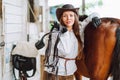 Confident horse woman cowgirl equestrienne hat, shirt, belt. Caring animal. Holding harness. Horseback riding