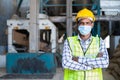 confident Industrial worker standing with medical face mask crossed arms by looking at camera at factory - concept of