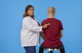 Confident internist woman using stethoscope on back of unrecognizable patient Royalty Free Stock Photo