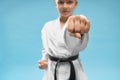 Confident junior in white kimono practicing punching.