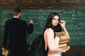 Confident in knowledge. Woman student look in glasses with book stack and backpack with teacher man writing on