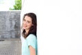 Confident lady smiling leaning against white wall