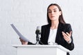 confident lecturer gesturing while speaking into microphone on podium tribune.