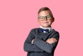 Confident little boy with crossed hands isolated on pink. Smart school kid in glasses, butterfly tie. Nerd child Royalty Free Stock Photo