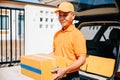 A confident logistic worker in uniform delivers cardboard boxes